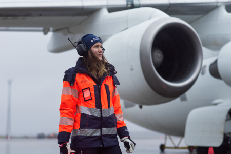 Kvinnlig Swedaviamedarbetare står framför ett flygplan 