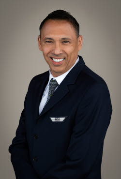 Man with short hair dressed in suit and tie smiling at the camera.