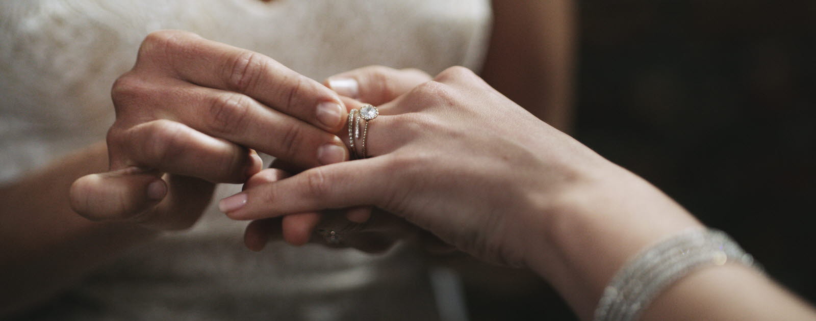 Kvinna i vit spets sätter en ring på en kvinnlig hand.