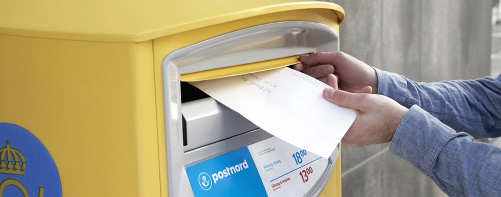 En person lägger ett kuvert i en brevlåda.