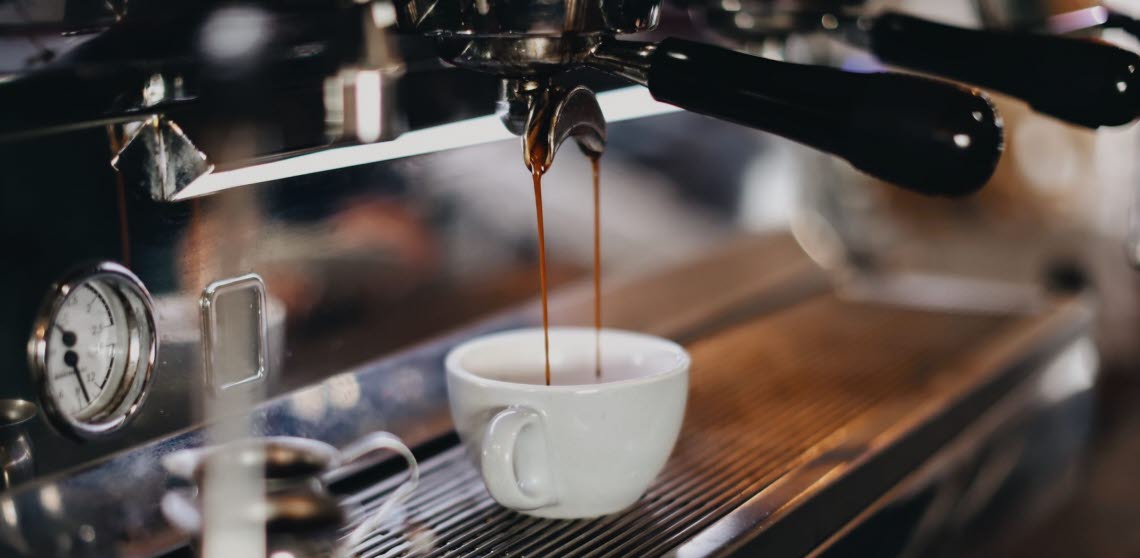 Kaffe rinner från espressomaskin in i en kopp.