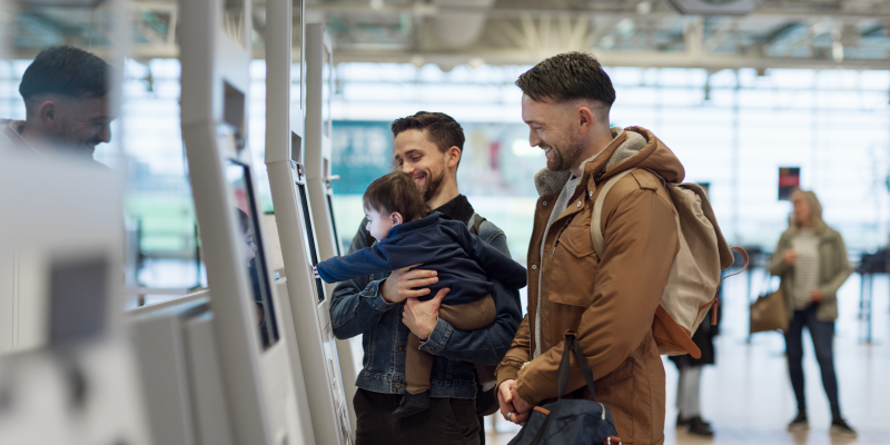 Two men and a child using a check-in kiosk