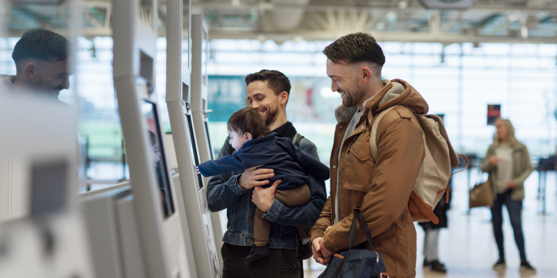 Två män och ett barn använder check-in automaten