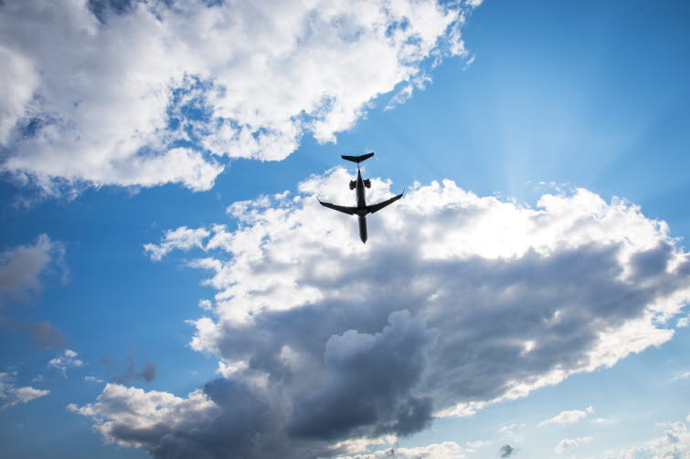Flygplan i luften mot blå himmel och moln