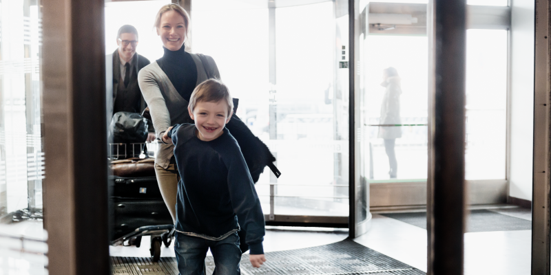 Pojke håller kvinna i handen vid ingången till terminal på Arlanda