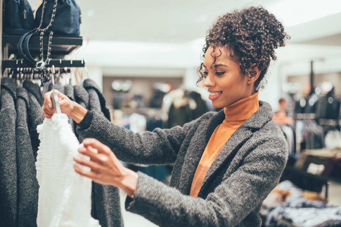 Woman in clothing store holding up a blouse.