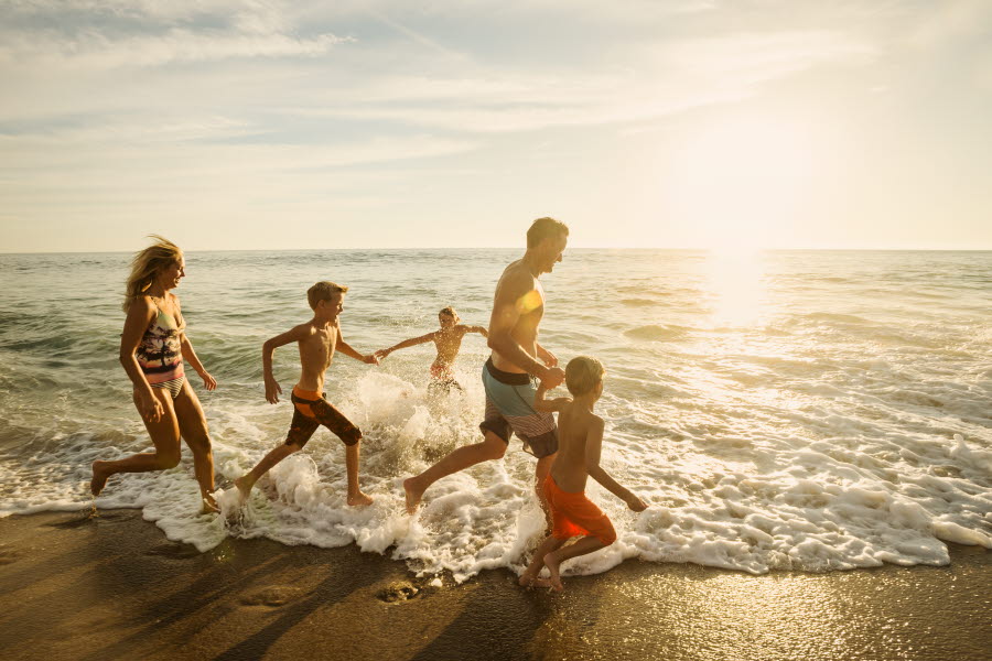 Familj som springer på stranden