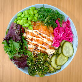 Bowl with broccoli, salad, edamame beans, cucumber, pickled onion, seaweed and salmon.