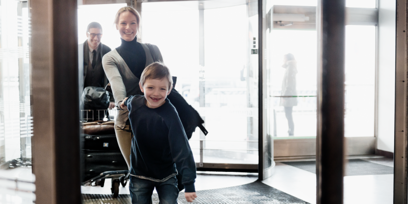 Pojke håller kvinna i handen vid ingången till terminal på Arlanda