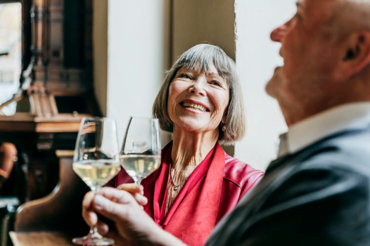 Older man and woman holding wine glasses and laughing.