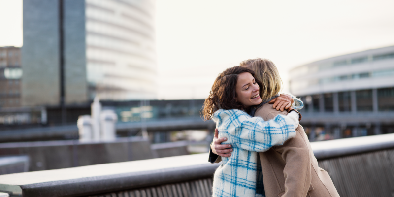 Two persons hug outside the terminal.