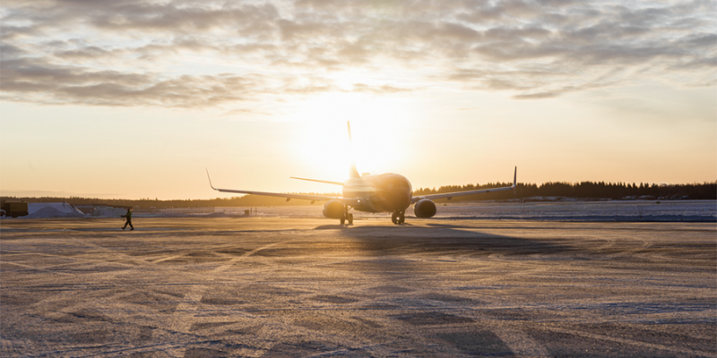 Flygplan i motljus vid soluppgång på frostig asfalt.
